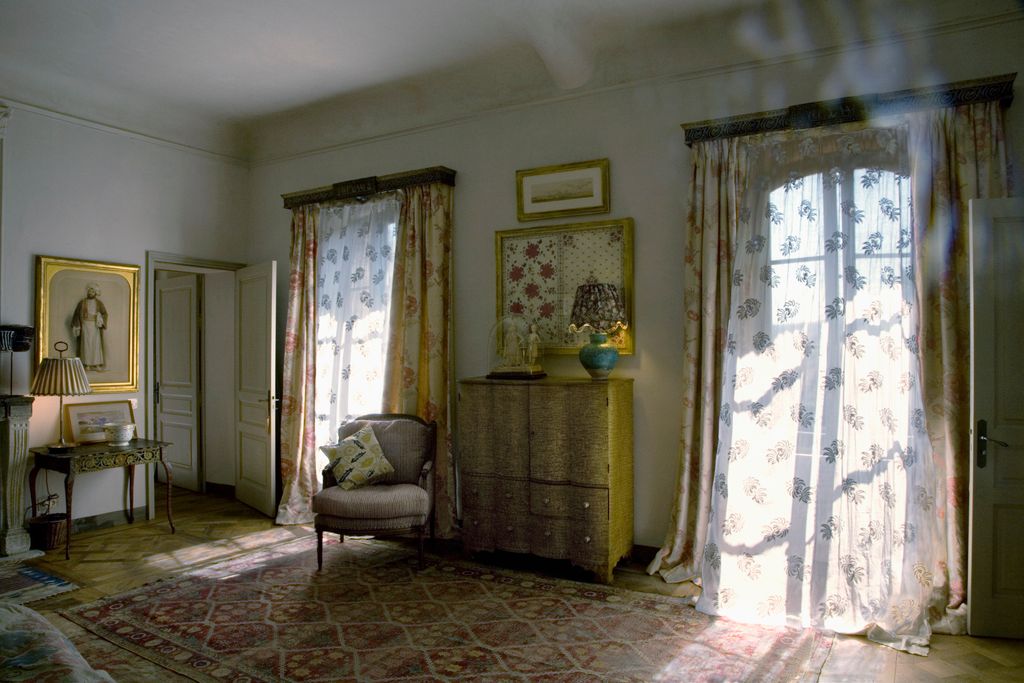 An Ottoman chest of drawers stands between the windows in the main bedroom. The curtains are in Robert Kime's ‘Opium Poppy.