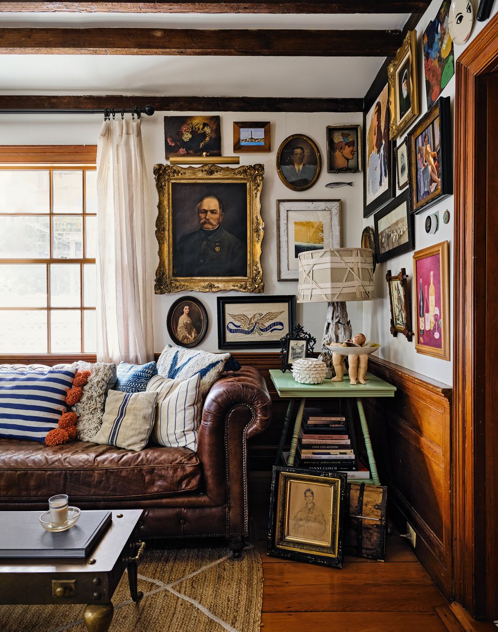 An eclectic array of artworks bought found and gifted over decades  fills the walls of the sitting room.