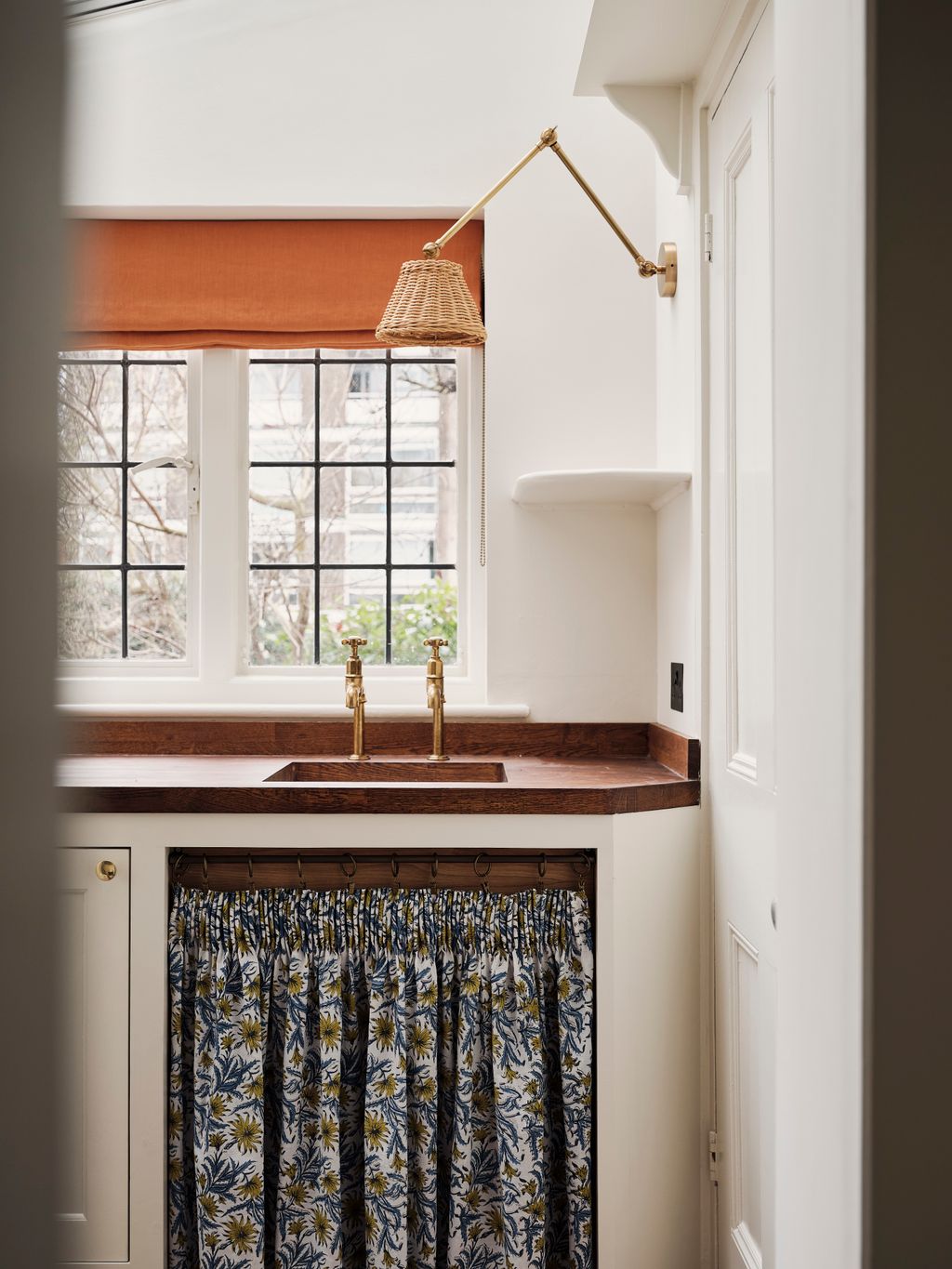 A blind in Tinsmiths' Washed Linen in mango adds a cheery touch in the utility room the under sink curtain is in ‘Flora...