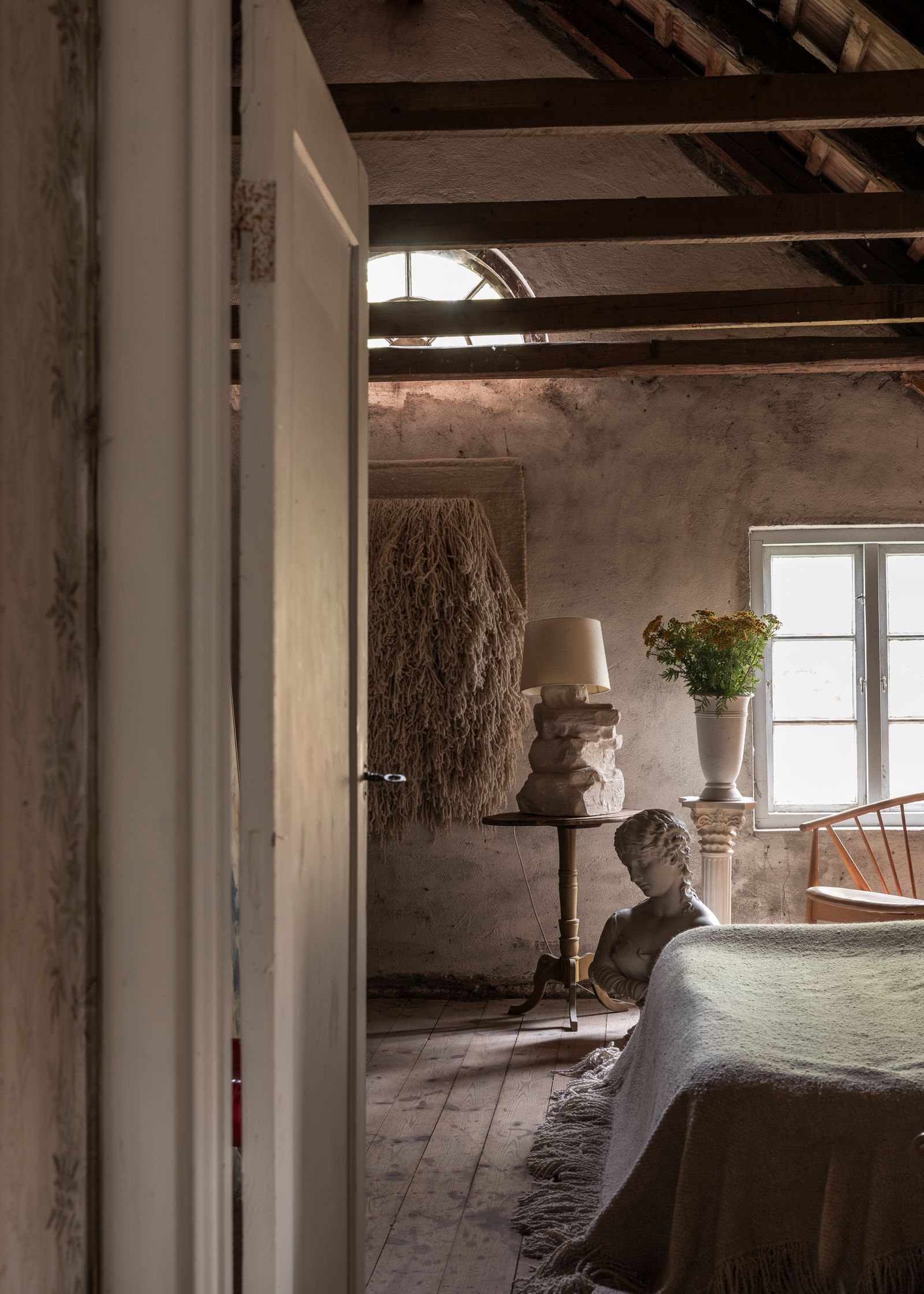 Their “summer bedroom” for guests features a tapestry and blankets from Cappelen Dimyr. The antique table and bust were...