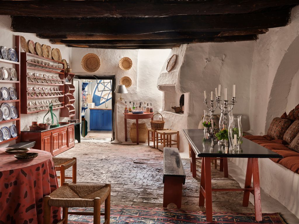 This room with its whitewashed arch has a long builtin stone seat with cushions and a locally made trestle table and...