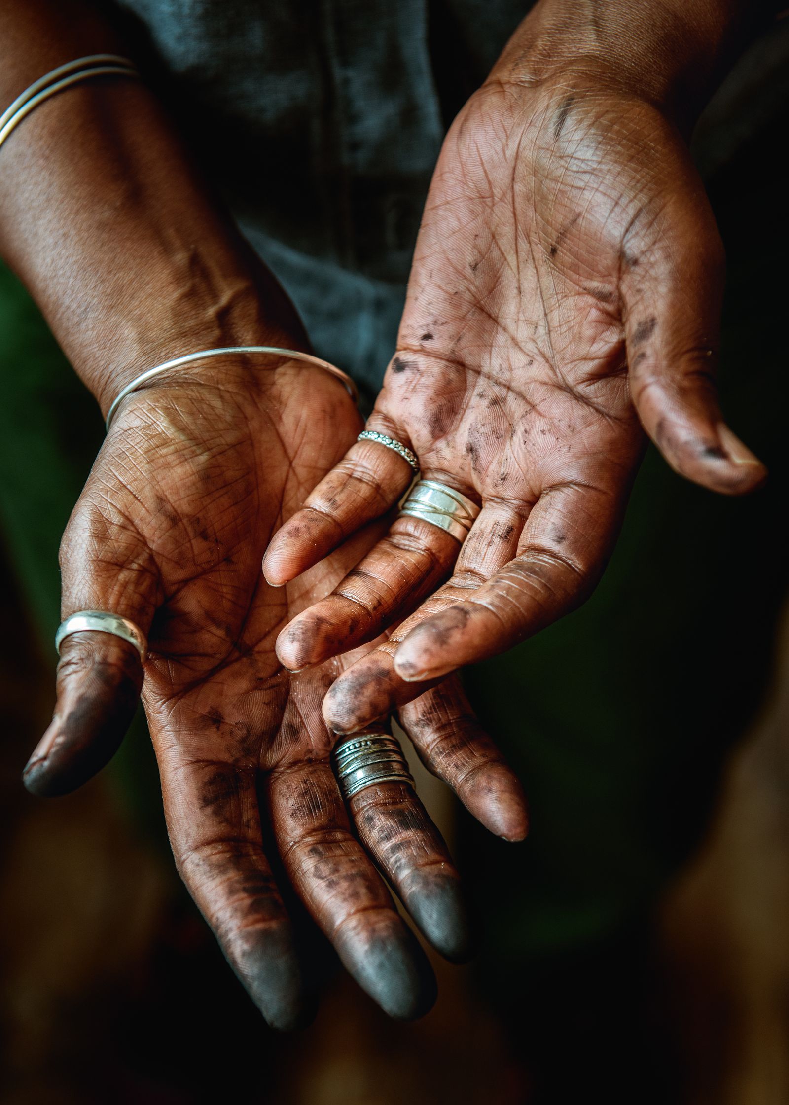 Barbara in her workspace her hands covered in charcoal.