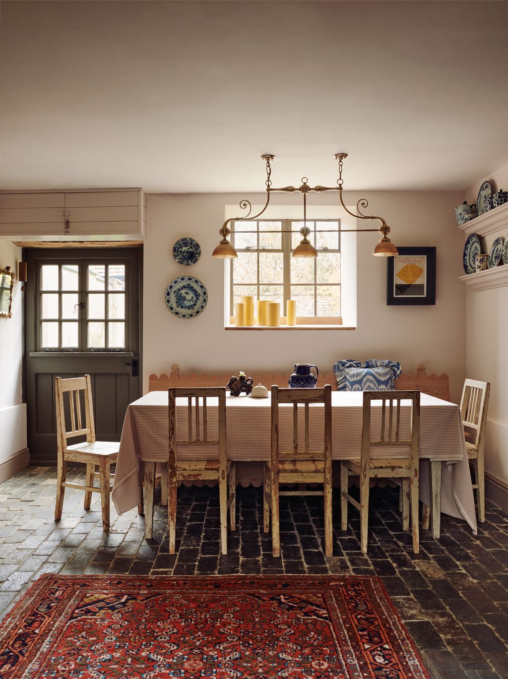 An antique copper light hangs above an old farmhouse table from a friend with distressed wooden chairs from Daylesford....