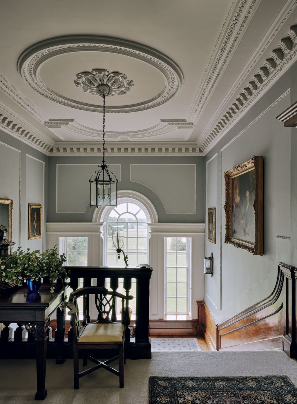 Image may contain Indoors Architecture Building Foyer Chair Furniture Lamp Home Decor Rug Art Painting and Plant