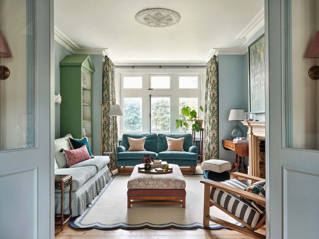 Image may contain Home Decor Lamp Couch Furniture Desk Table Rug Plant Chair and Window