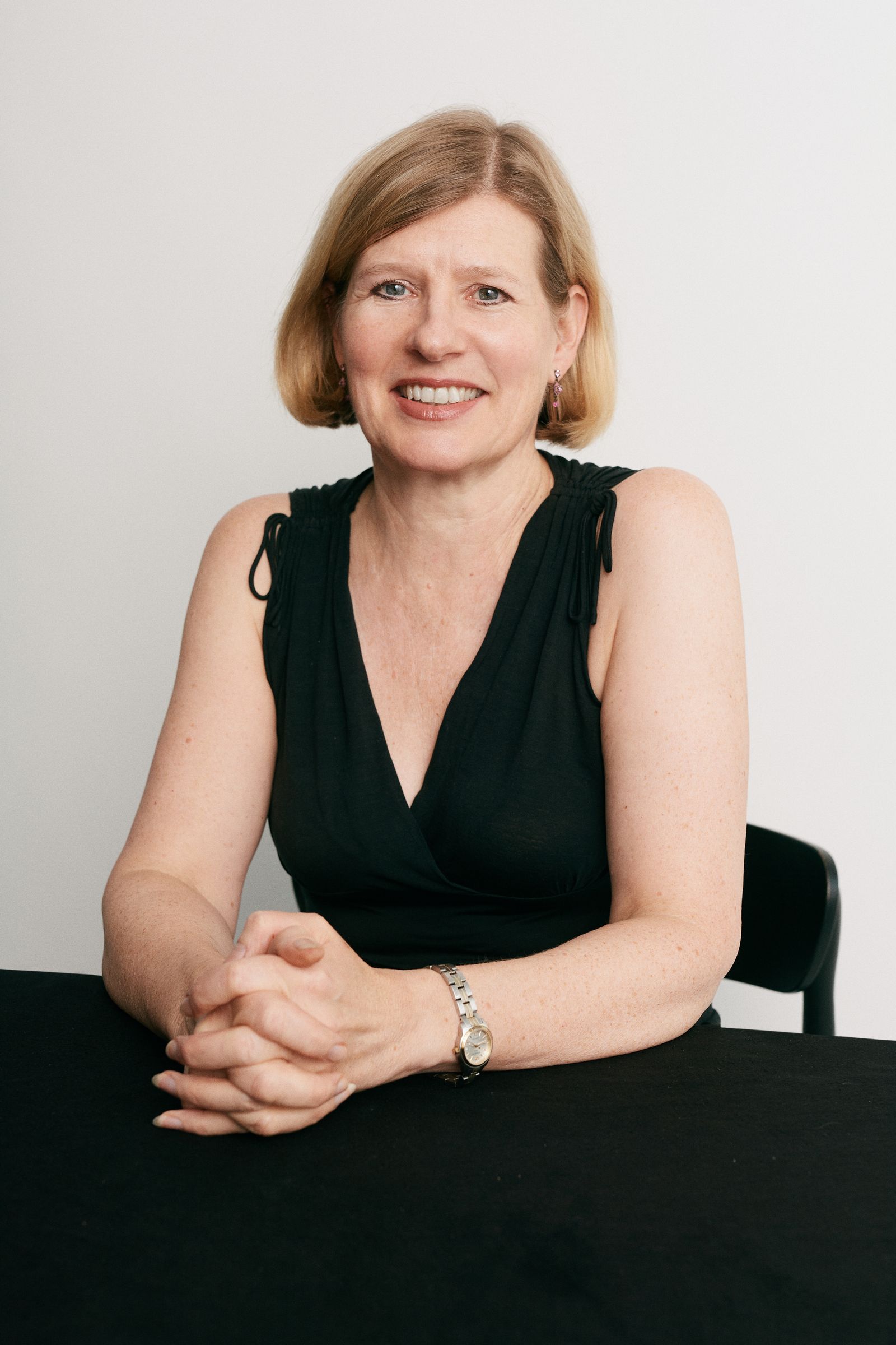 Image may contain Face Head Person Photography Portrait Happy Smile Desk Furniture Table Adult and Wristwatch