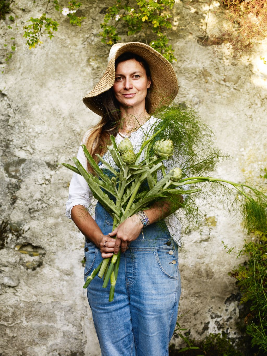 Image may contain Clothing Pants Adult Person Face Head Photography Portrait Hat Jeans and Flower