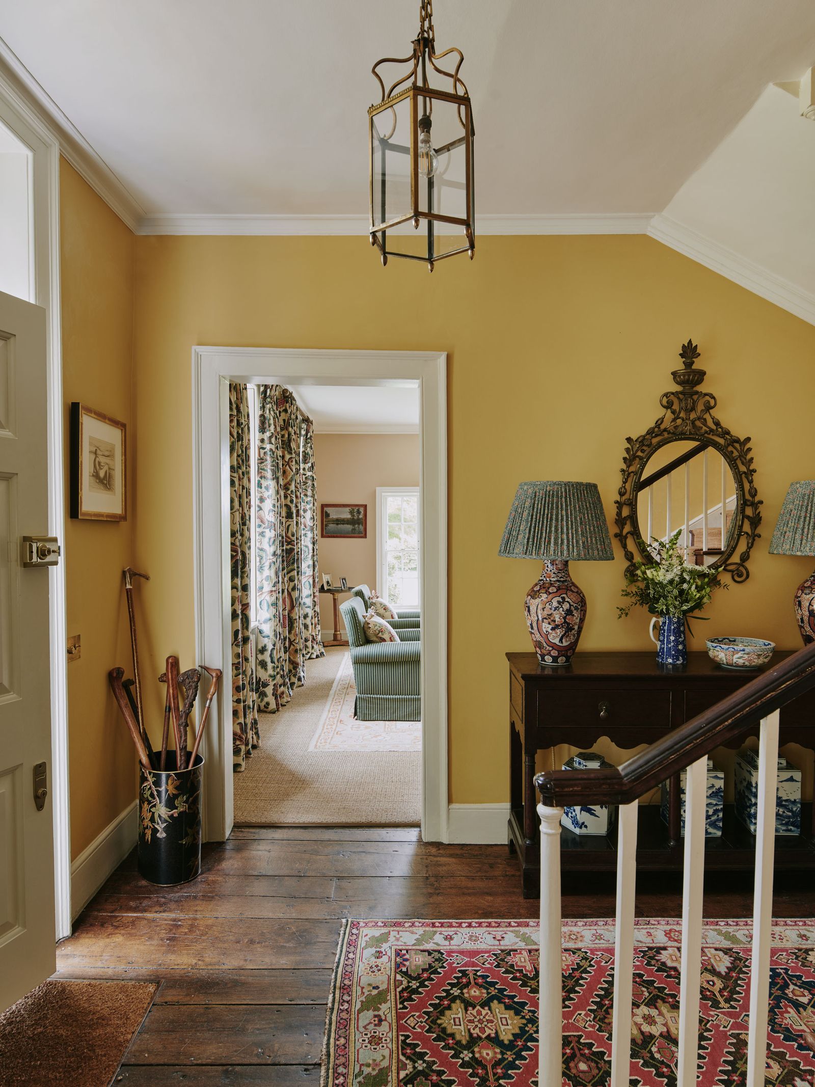 Image may contain Lamp Indoors Architecture Building Foyer Art Painting Home Decor Rug Plant Couch and Furniture