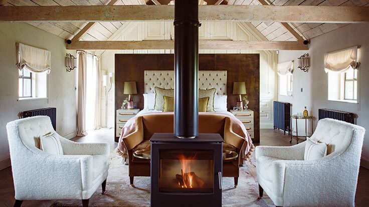 Image may contain: Fireplace, Indoors, Lamp, Bed, Furniture, Chair, Clothing, Footwear, Shoe, Hearth, and Home Decor