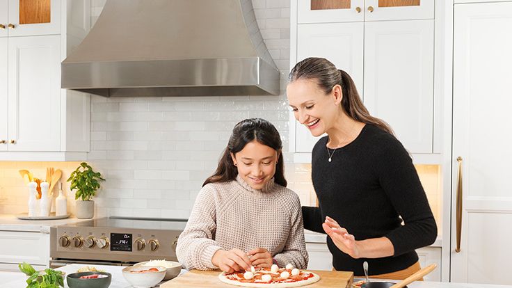 Image may contain: Jade Alleyne, Adult, Person, Plant, Cooktop, Indoors, Kitchen, Food, Pizza, Accessories, and Jewelry