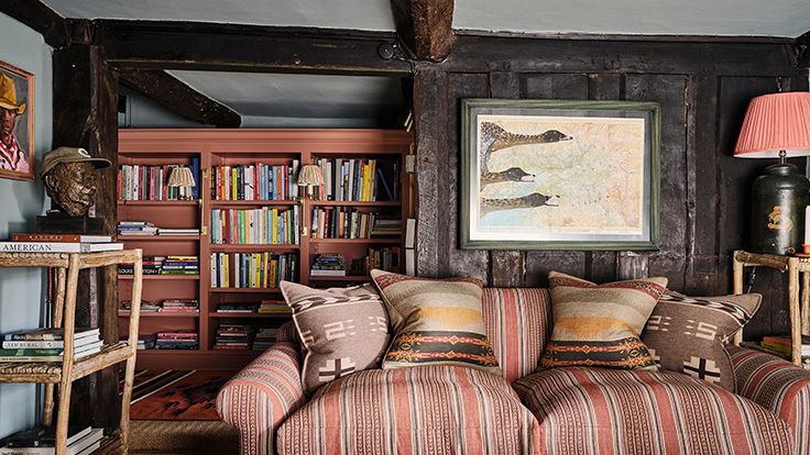 Image may contain: Home Decor, Lamp, Furniture, Art, Painting, Person, Couch, Cushion, Book, Publication, and Bookcase