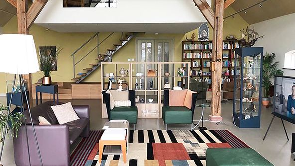 Image may contain: Home Decor, Plant, Couch, Furniture, Lamp, Chair, Rug, Person, Desk, Table, Indoors, and Bench