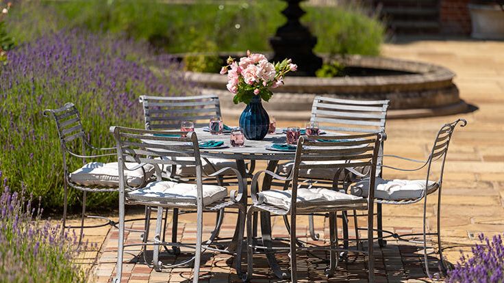 Image may contain: Furniture, Table, Dining Table, Tabletop, Path, Walkway, Chair, Flower, Plant, Cup, and Architecture