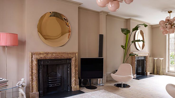 Image may contain: Home Decor, Lamp, Fireplace, Indoors, Chair, Furniture, Person, Rug, Electronics, and Speaker