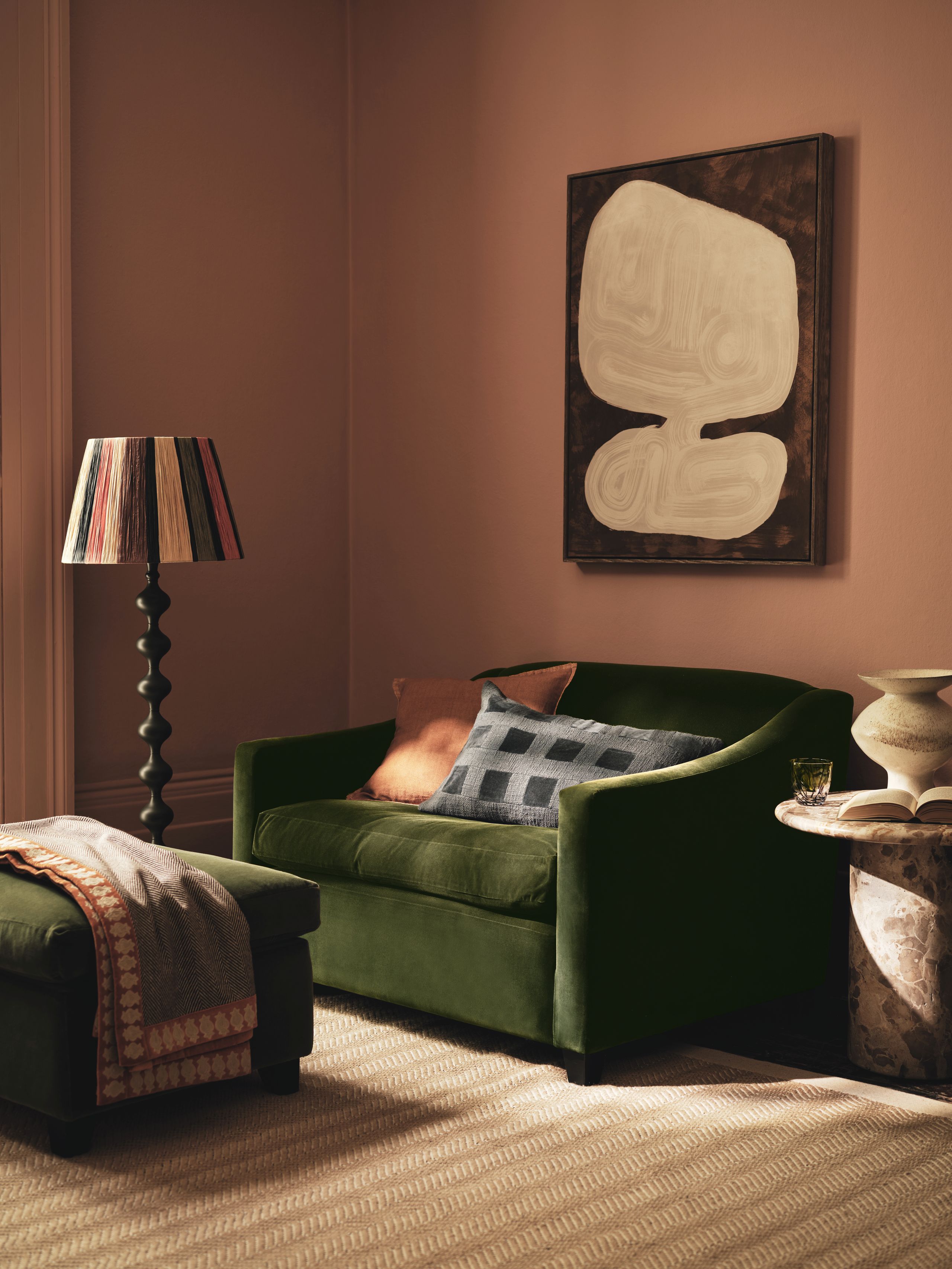 Image may contain: Lamp, Couch, Furniture, Art, Painting, Cup, Book, Publication, Home Decor, Chair, and Rug