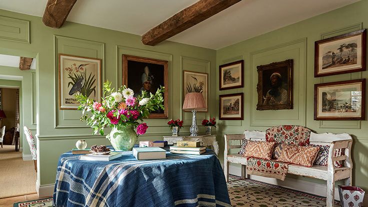 Image may contain: Home Decor, Lamp, Tablecloth, Art, Painting, Desk, Furniture, Table, Chair, Person, Rug, Bench, and Flower