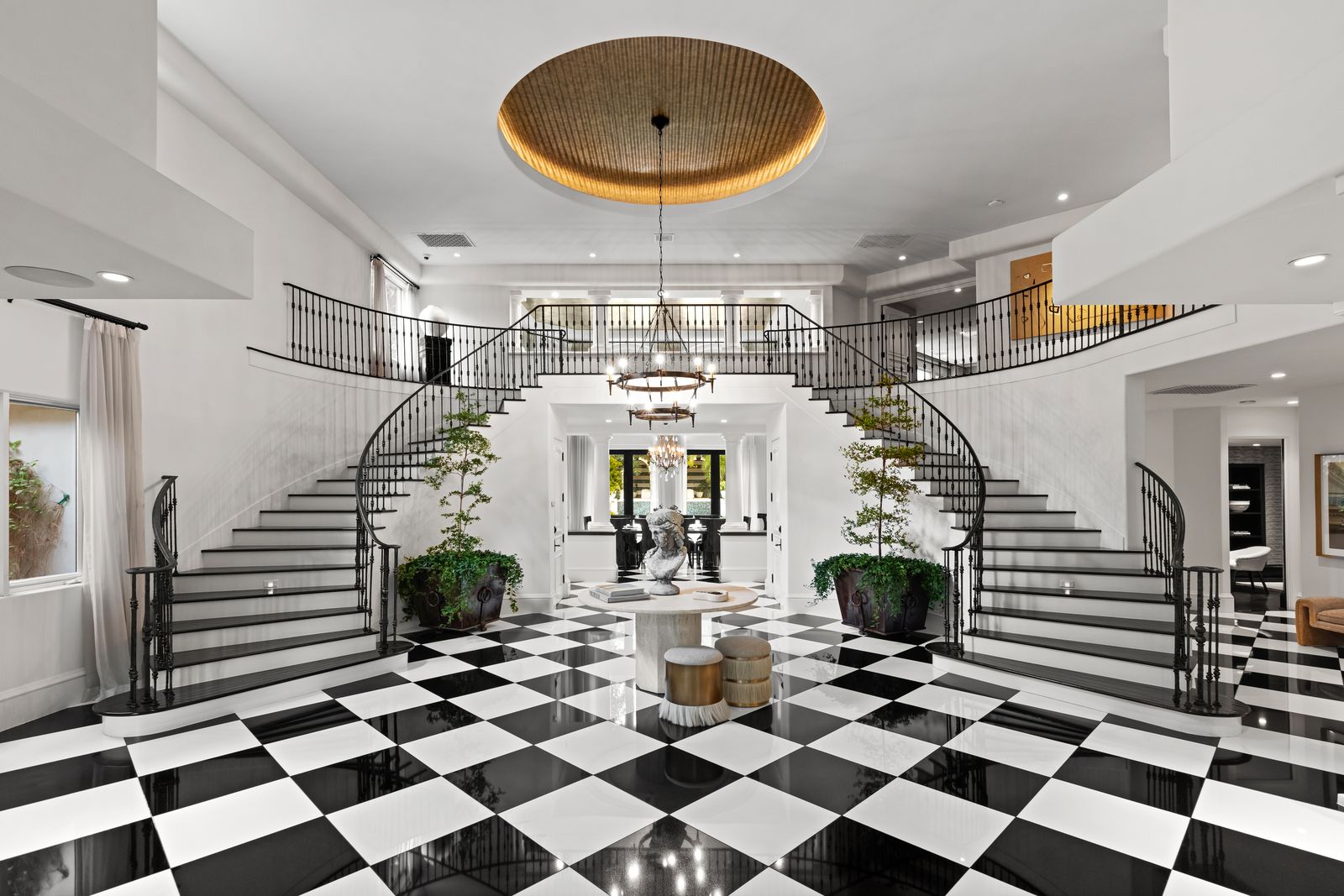 foyer in the former home of Kris Kardashian with blackandwhite checkerboard flooring dual stairway leading up to second...