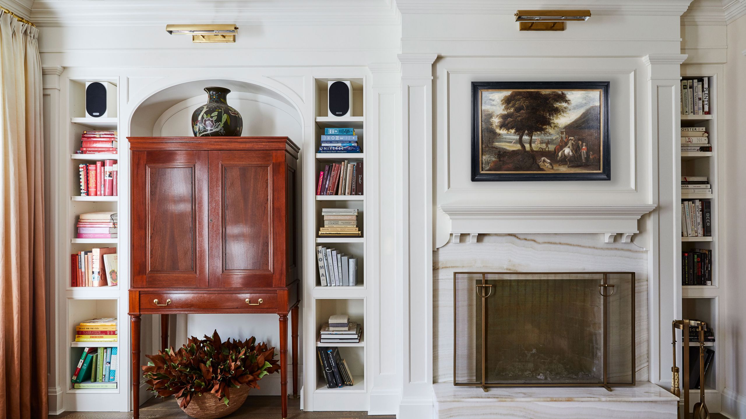 Image may contain: Indoors, Interior Design, Plant, Furniture, Fireplace, Wood, Lamp, Bookcase, Art, and Painting