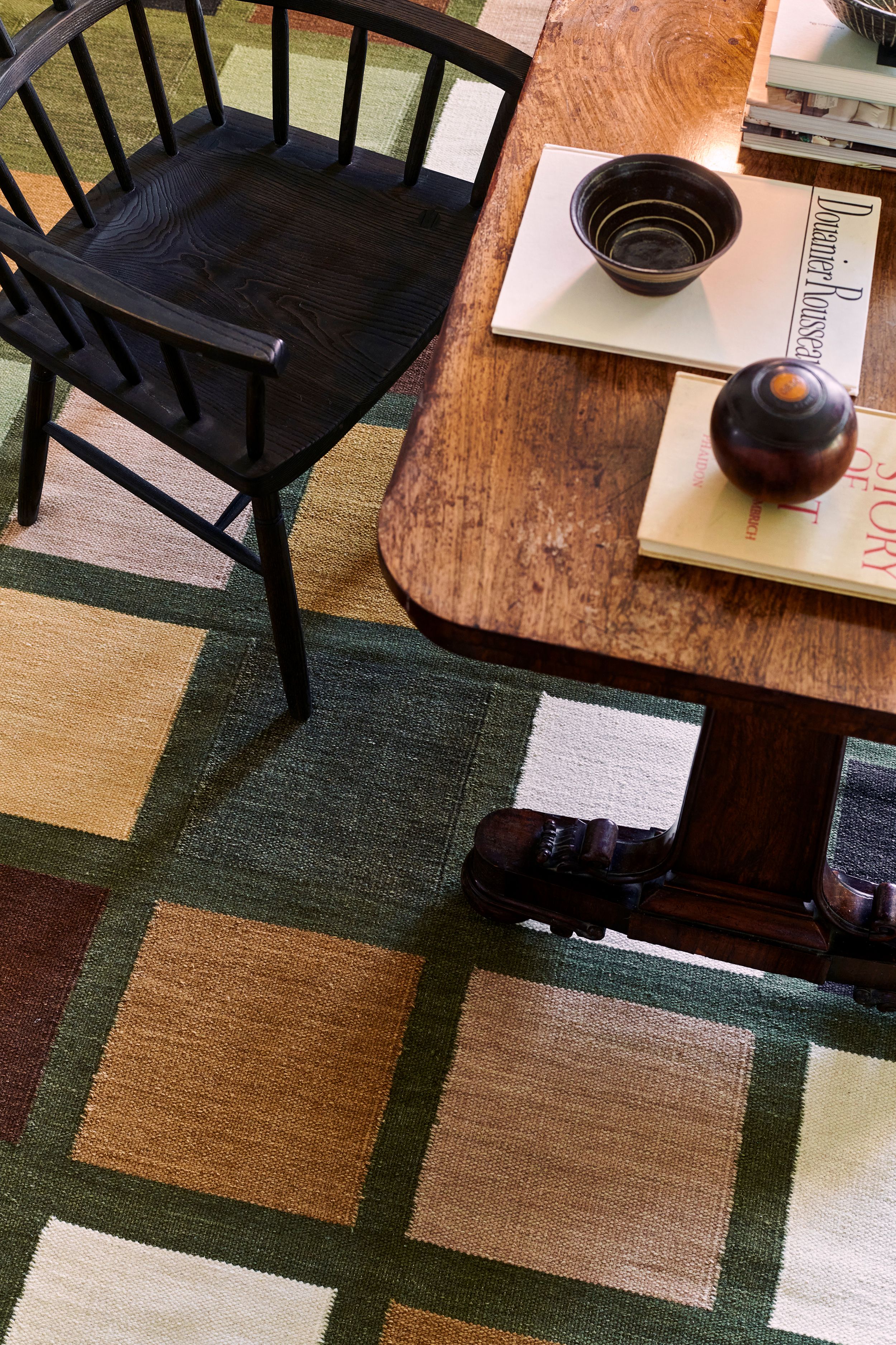 Image may contain: Home Decor, Rug, Furniture, Table, Book, Publication, Coffee Table, Chair, Wood, Floor, and Flooring