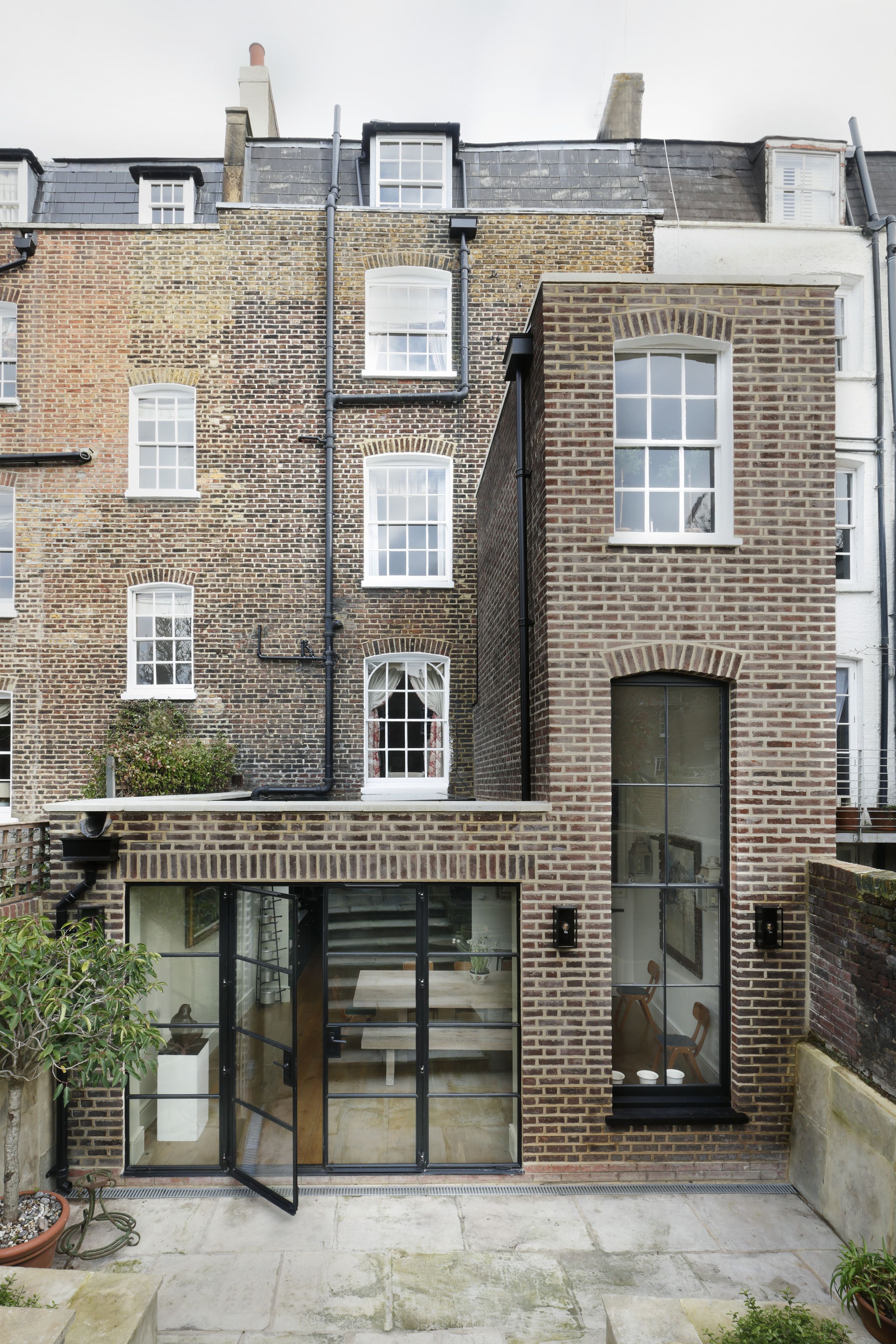 Image may contain: Plant, Architecture, Building, Housing, Door, House, Chair, Furniture, Lamp, and Row House