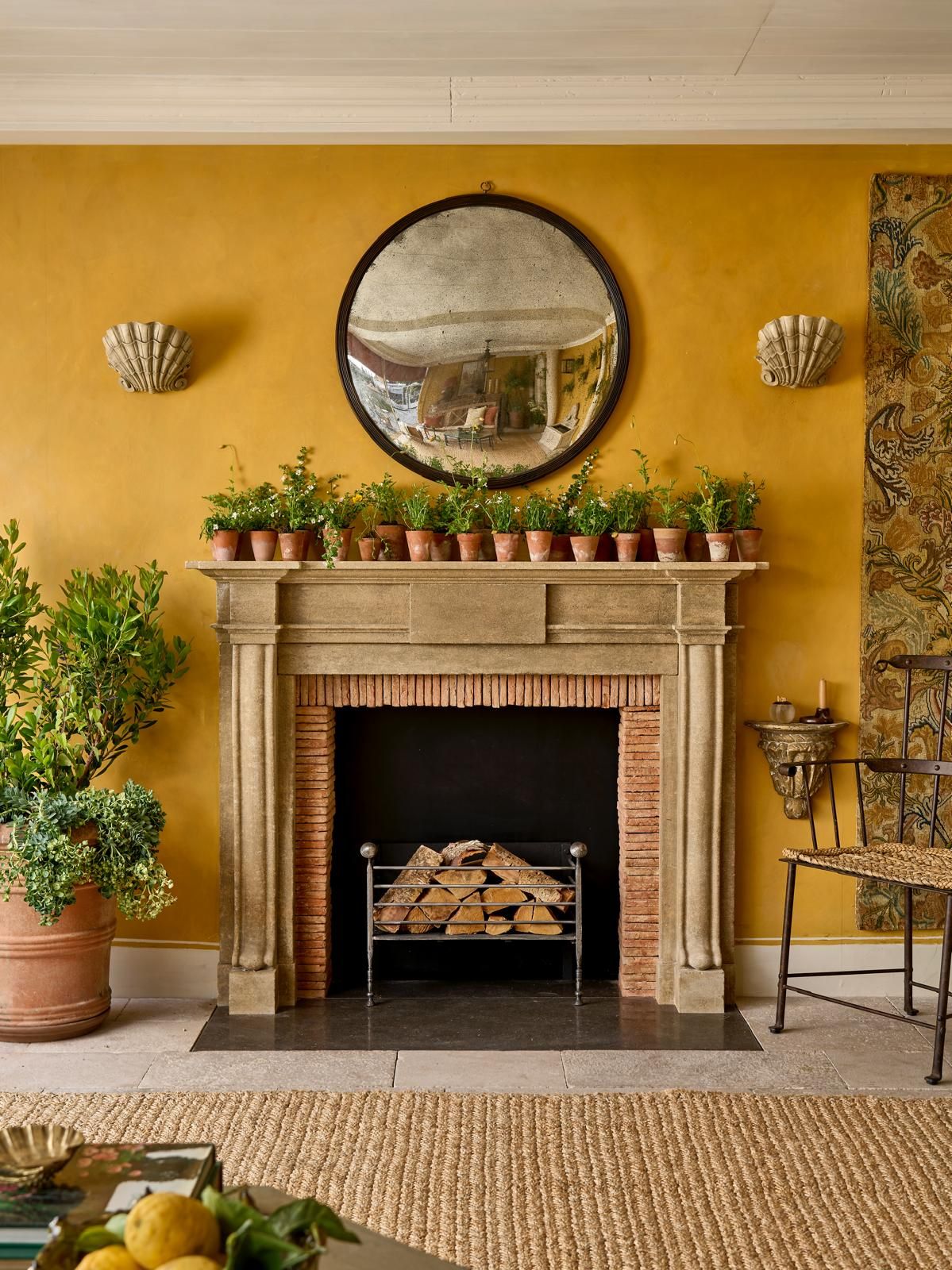 Image may contain: Fireplace, Indoors, Interior Design, Chair, Furniture, Plant, Home Decor, Rug, Hearth, Candle, and Lamp