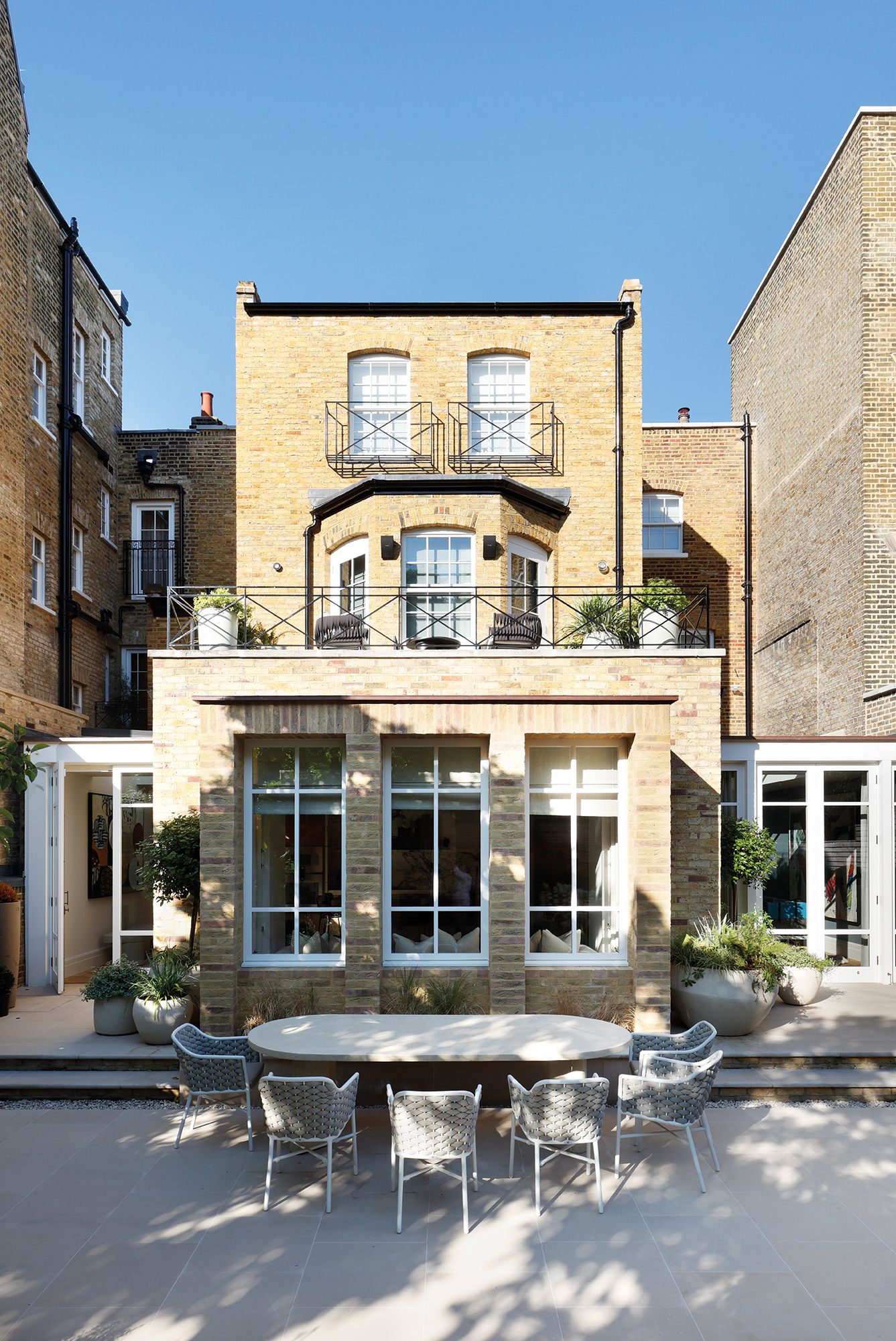 Image may contain: Door, Chair, Furniture, Plant, City, Architecture, Building, Housing, Desk, Table, Person, and House