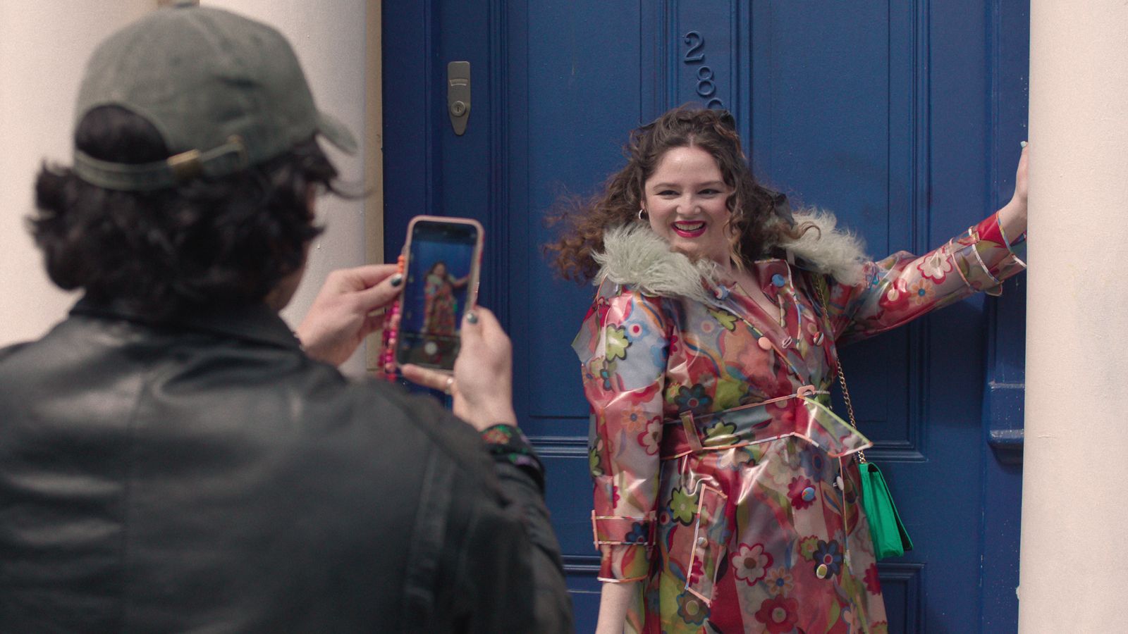 Image may contain Clothing Coat Jacket Adult Person Photography Electronics Mobile Phone Phone Hat and Accessories