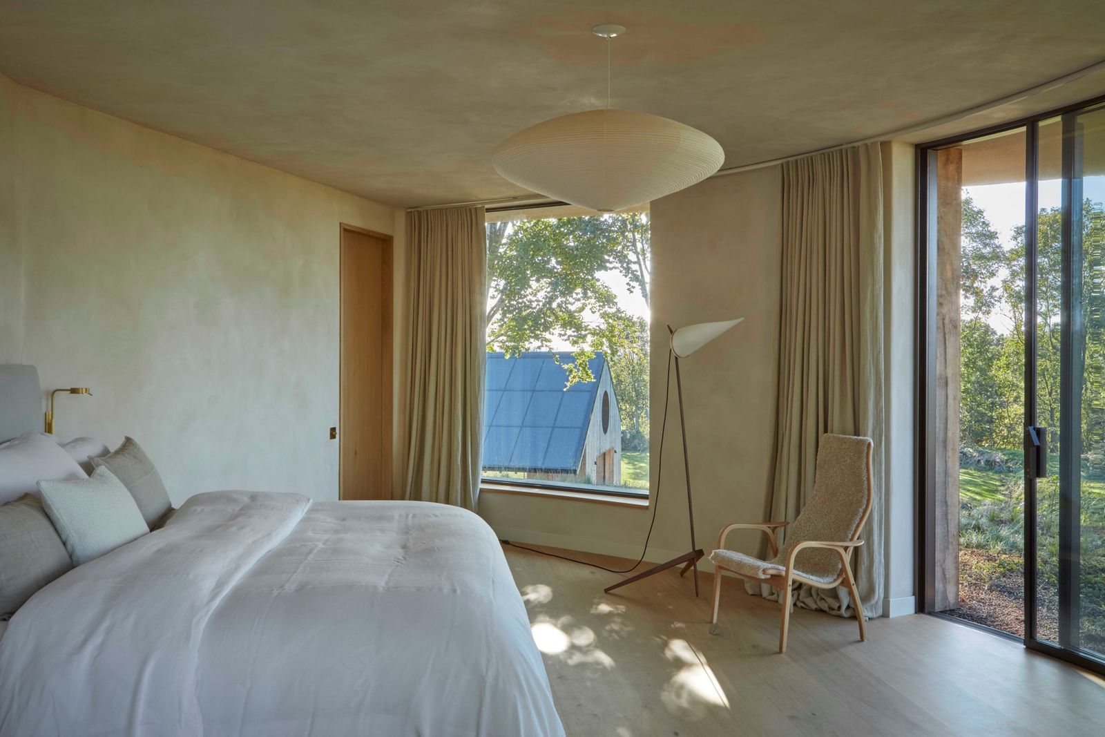 The master bedroom looks out across the leaf point over the living roof to the fields beyond. A Noguchi pendant and...