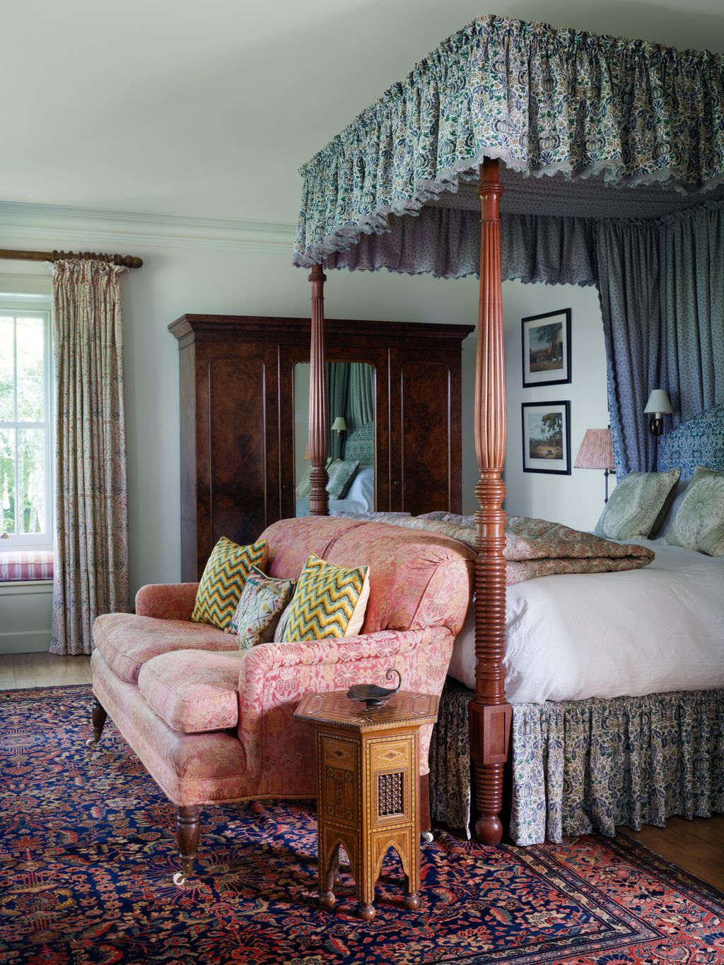 In the main bedroom at the foot of an antique Irish fourposter bed with hangings in Morris  Cos ‘Little Chintz...