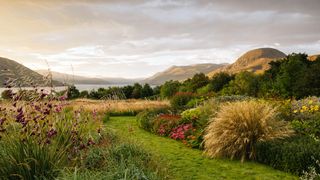 Showcasing views of Little Loch Broom and the rounded hummock of Sail Mòhr a grass path leads towards a large circular...