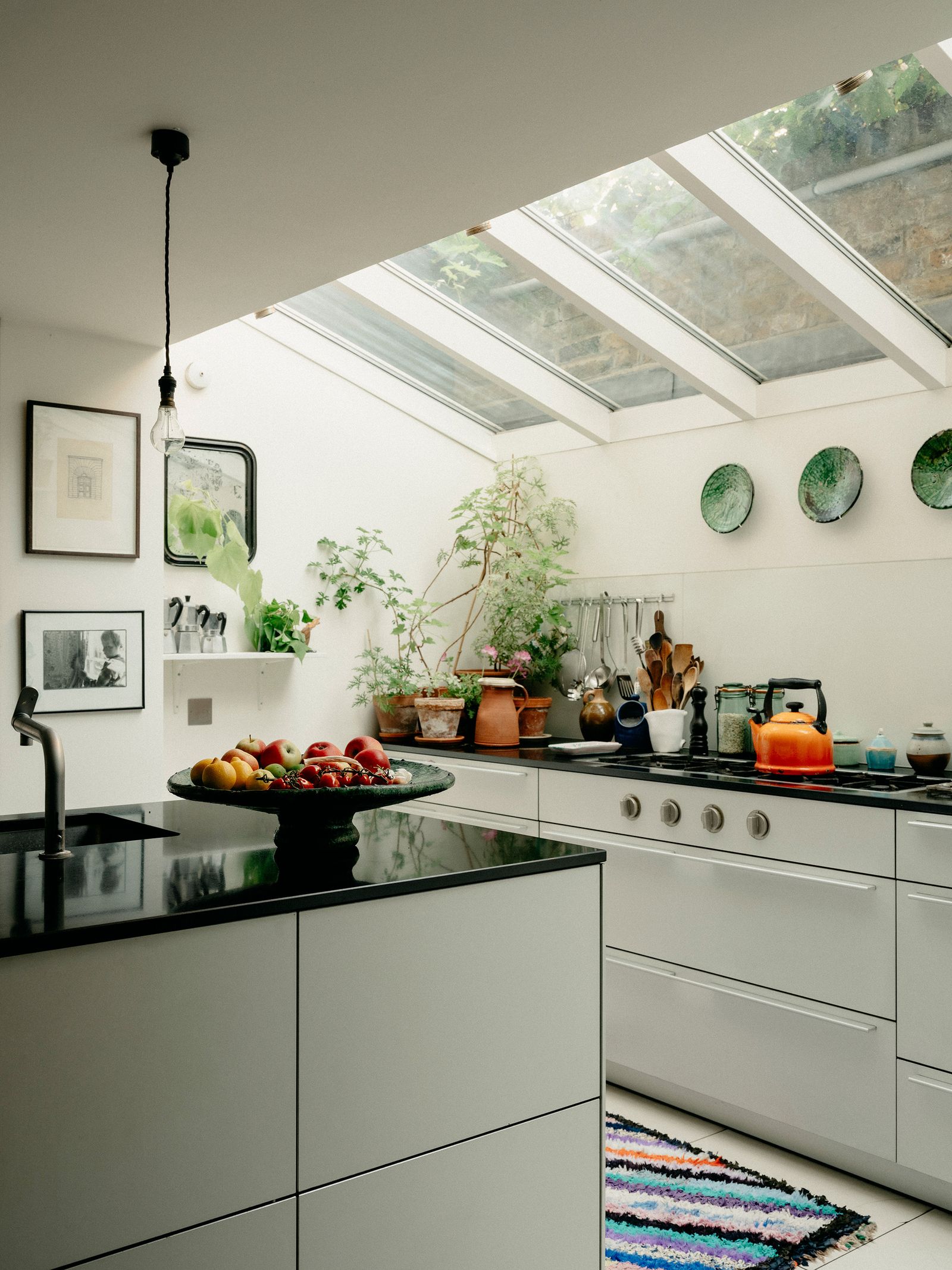 The kitchen was extended out into the garden. The gloss black worktops reflect the light and the plates are from Fez...