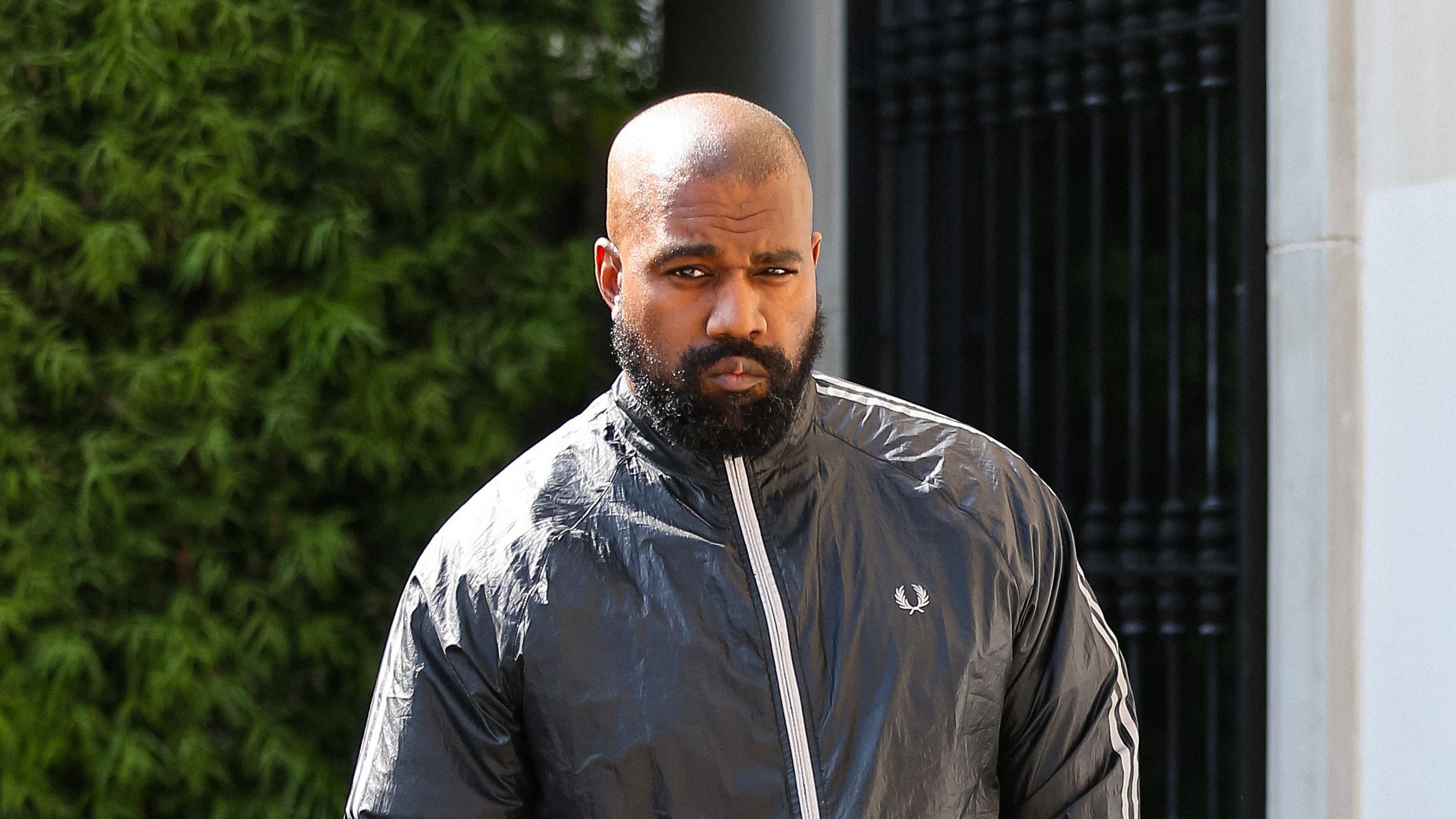Kanye West in black outfit holding phone