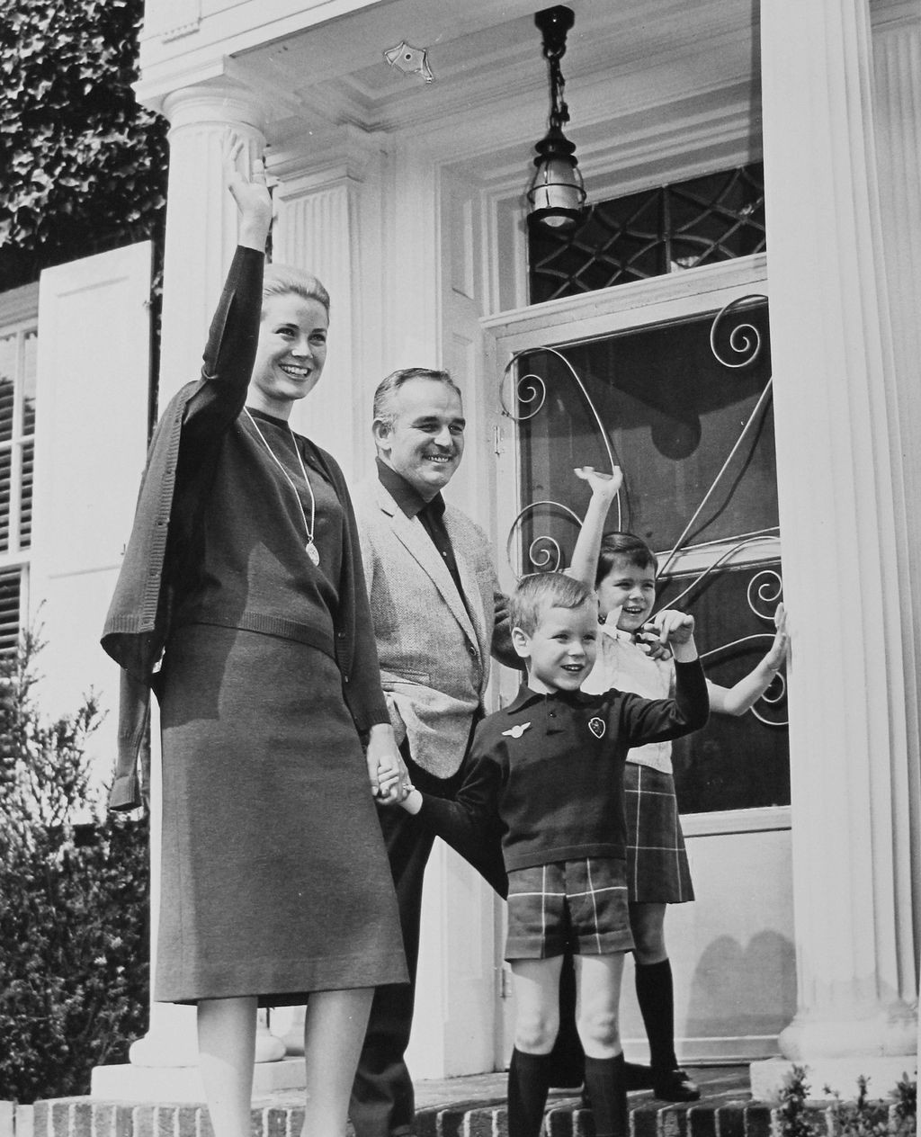 blackandwhite photo of Grace Kelly Prince Rainier young Albert and Caroline waving standing in doorway of Kellys former...